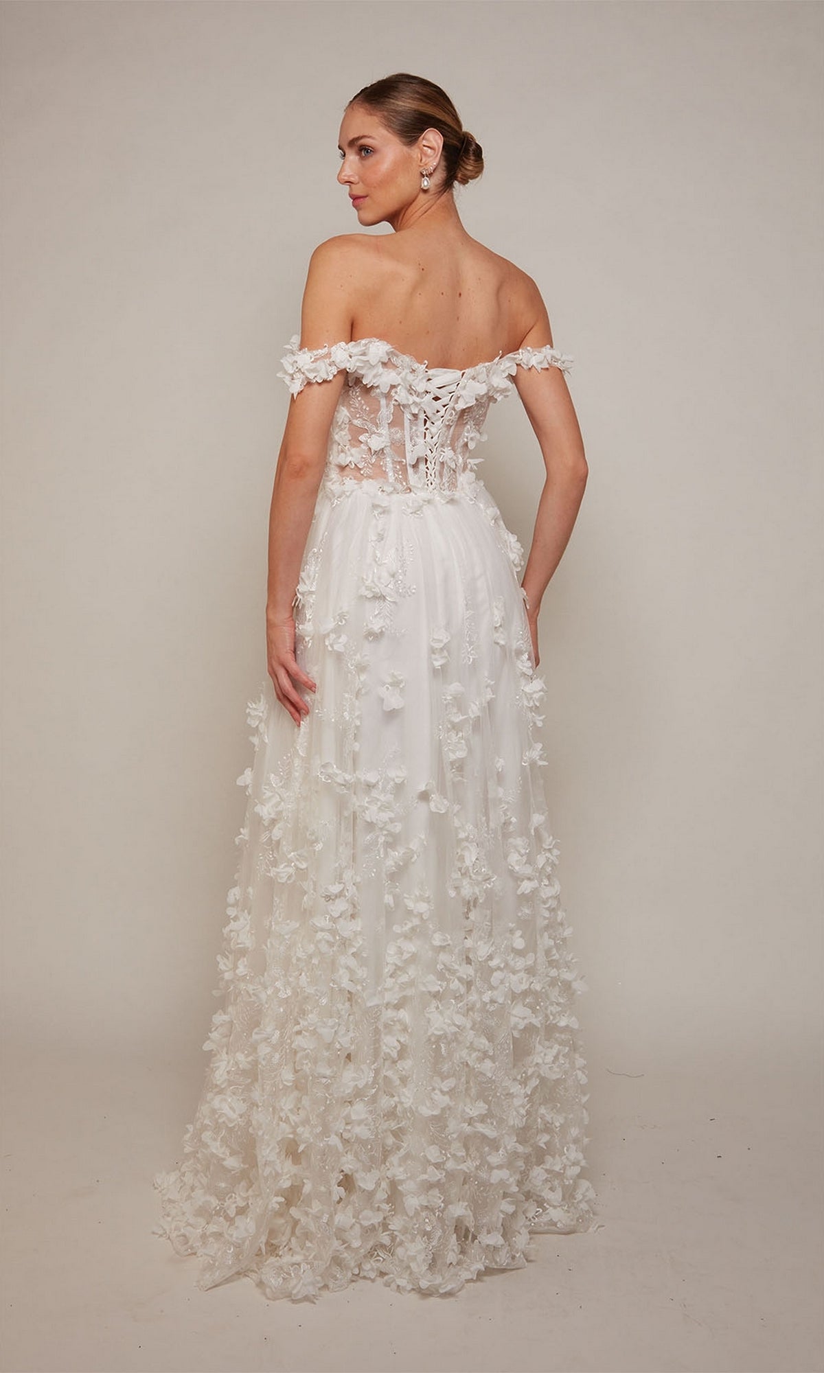 A woman wearing the Alyce 61308 Off-Shoulder Long Floral Dress, featuring floral appliqués and a lace-up back, poses elegantly against a plain background.